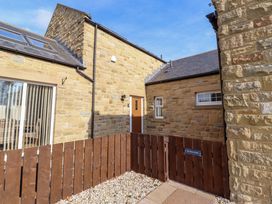 An outdoor area with a stone wall, fence, and a door at Roe Deer in Lucker