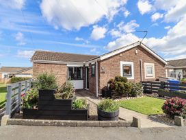 A house with a garden and flower bed at Flora Cottage Beadnell