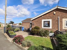 An outdoor area with flower beds and a house at Flora Cottage Beadnell