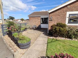 A garden with flower beds and seating at Flora Cottage Beadnell
