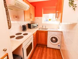 A kitchen with an oven, stove, microwave, kettle, sink, and washing machine at Flora Cottage Beadnell