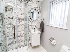 A bathroom with a shower, sink, and toilet at Flora Cottage in Beadnell