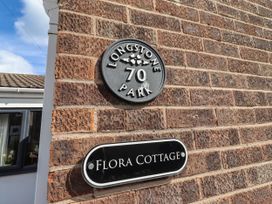 A street name sign and house number on a brick wall at Flora Cottage in Beadnell