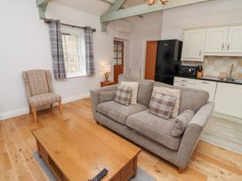 A living room with a sofa and kitchen area at Chiff Chaff in Lucker