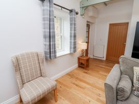 A living room with curtains, a chair, a lamp and a sofa at Chiff Chaff in Lucker