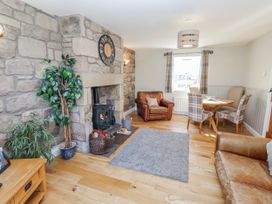 A living room with a fireplace and dining area at Greenfinch in Lucker