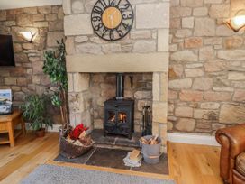 A living room with a fireplace and clock at Greenfinch in Lucker