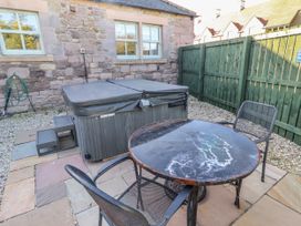 A garden with hot tub and table with chairs at Greenfinch in Lucker