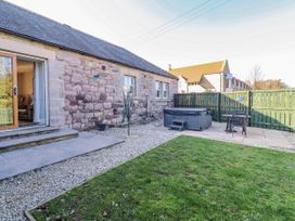 A garden with a hot tub and chairs at Greenfinch in Lucker