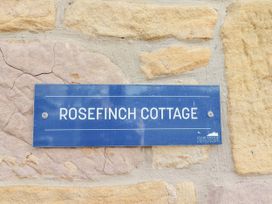 A sign reading Rosefinch Cottage on a stone wall at Rosefinch in Lucker