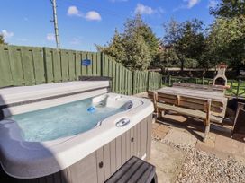 A hot tub with an outdoor table and wooden bench at Rosefinch in Lucker