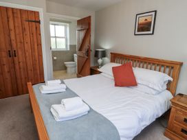 A bedroom with a bed and bathroom access at Rosefinch in Lucker