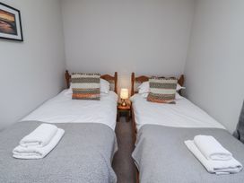 A bedroom with two single beds and a lamp at Rosefinch in Lucker