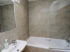 A bathroom with a bath tub and sink at Rosefinch in Lucker