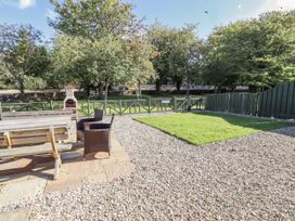 A garden with gravel, grass, table, chairs and barbecue at Rosefinch in Lucker
