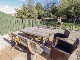 A garden with a wooden table and chairs at Rosefinch in Lucker