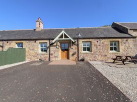 An outdoor area with a stone building and seating at Chaffinch in Lucker