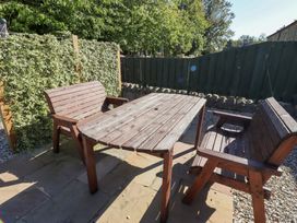 A garden with a wooden table and chairs at Chaffinch in Lucker