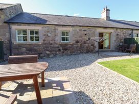 A patio area with a wooden table and chairs at Chaffinch in Lucker