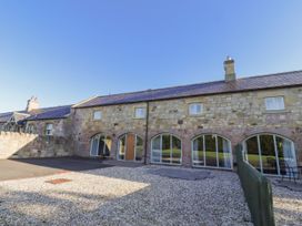 An outdoor area with a stone wall and large windows at Goldfinch in Lucker