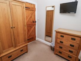 A bedroom with a wardrobe, mirror, chest of drawers, and television at Goldfinch in Lucker