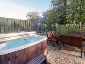 An outdoor area with a hot tub and wooden furniture at Goldfinch in Lucker
