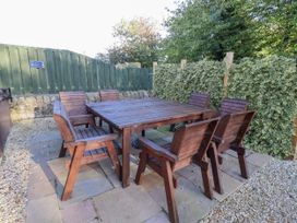 A garden with a wooden table and chairs at Goldfinch in Lucker