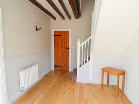 A hallway with a staircase and wooden door at Bullfinch in Lucker