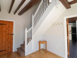 A hallway with a staircase and wooden door at Bullfinch in Lucker