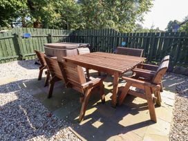 A garden area with a wooden table, chairs and a hot tub at Bullfinch in Lucker