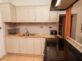 A kitchen with cabinets, sink, and toaster at Adderstone Cottage in Bamburgh