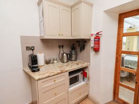 A kitchen with cabinets, coffee maker, kettle, and microwave at Adderstone Cottage in Bamburgh