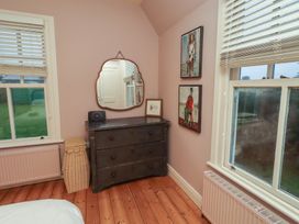 A bedroom with a dresser and paintings at Armstrong Cottages No6 Bamburgh