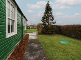 A garden with a green building and grass area at Armstrong Cottages No6 Bamburgh