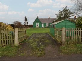 A garden with a green house and fence at Armstrong Cottages No6 in Bamburgh