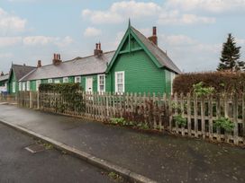 A green house with a fence and bushes at Armstrong Cottages No6 Bamburgh