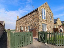 A stone house with a green fence and gate at Pipistrelle in Bamburgh