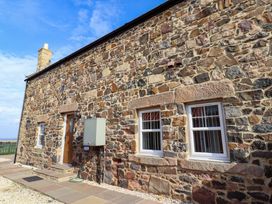 An exterior view of a stone building with windows and a wooden door at Pipistrelle in Bamburgh