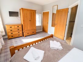 A bedroom with a bed, wardrobe, dresser, and television at Pipistrelle in Bamburgh