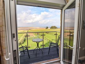 A balcony with a table and chairs overlooking a field at Pipistrelle in Bamburgh