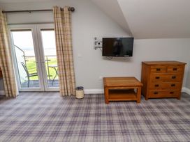A bedroom with a television and a balcony at Pipistrelle in Bamburgh