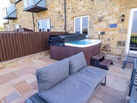 A patio area with a hot tub and sofa at Pipistrelle in Bamburgh