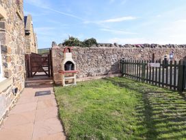 An outdoor area with a stone wall and a barbecue at Pipistrelle in Bamburgh
