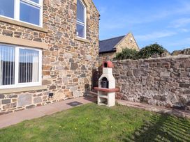 An outdoor area with a stone wall and a barbecue at Pipistrelle in Bamburgh