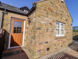 An outdoor area with a stone wall and door at Goosander in Bamburgh