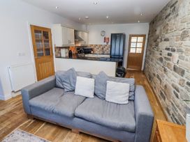 A living room with a sofa and kitchen area at Goosander in Bamburgh