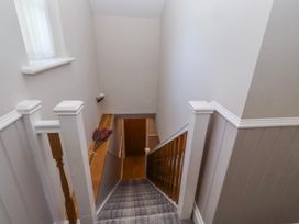 A staircase with a handrail and a door at Goosander in Bamburgh