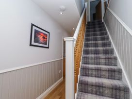 A hallway with a staircase and artwork at Goosander in Bamburgh