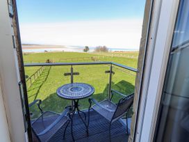 A balcony with table and chairs overlooking a green field at Goosander in Bamburgh