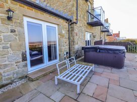 An outdoor area with a hot tub and glass doors at Goosander in Bamburgh